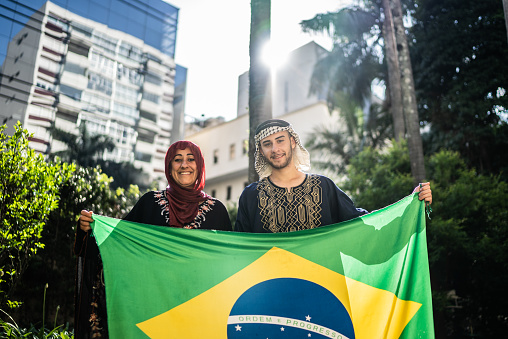 Mother and son holding Brazilian flag outdoors