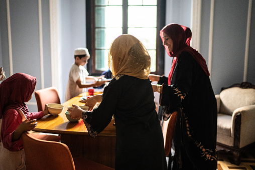 Islamic family arranging table and serving food at home