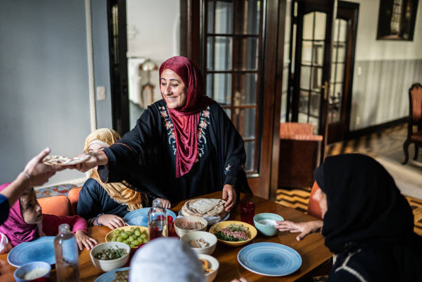 islamische familie beim gemeinsamen mittagessen zu hause - zurückhaltende kleidung stock-fotos und bilder