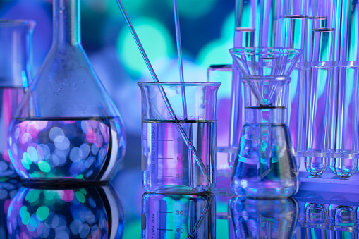 Glass tubes and beakers on blue bokeh background.