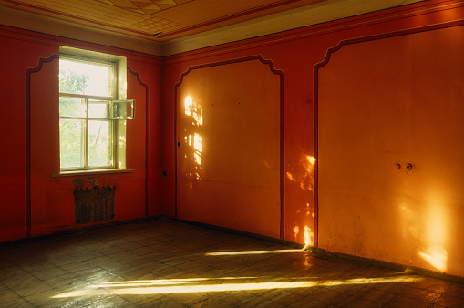 A room in an abandoned building, the warm summer sun shines through a dirty window, the empty space is crossed by patches of light and shadow, the old walls are painted in vintage style, an atmospheric scene