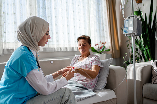 Muslim woman Health visitor and a senior woman during home visit. A nurse or a doctor examining a woman.
