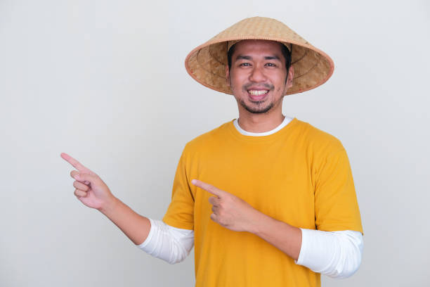 istock Young Indonesian farmer smiling at camera and pointing to the right side 1440499046