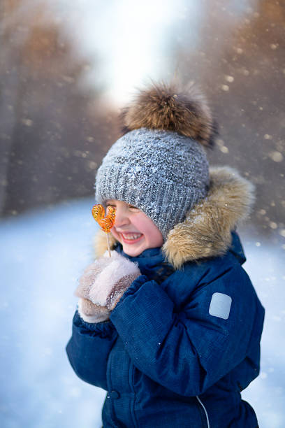 istock child boy holding lollipop outdoors in winter 1440499214