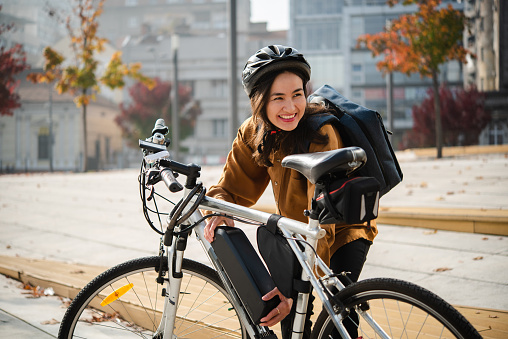 Portrait of a beautiful Asian woman preparing to go to work on an electric bike