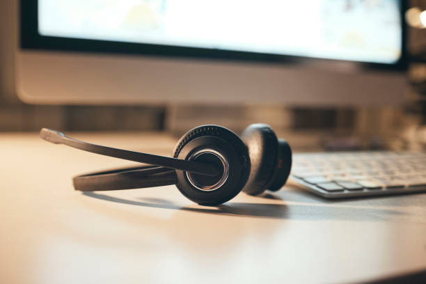Headset, call center and empty night office desk computer in contact us, crm consulting and telemarketing company. Zoom, headphones and customer support audio equipment on table with sales technology