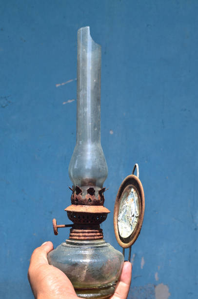 istock Hand holding old and rusty oil lamp on blue background. 1440504031
