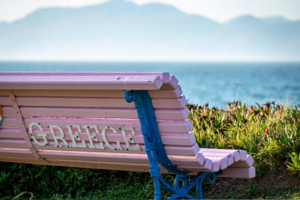 banco con la escritura grecia frente al mar - outdoors store beach bench fotografías e imágenes de stock