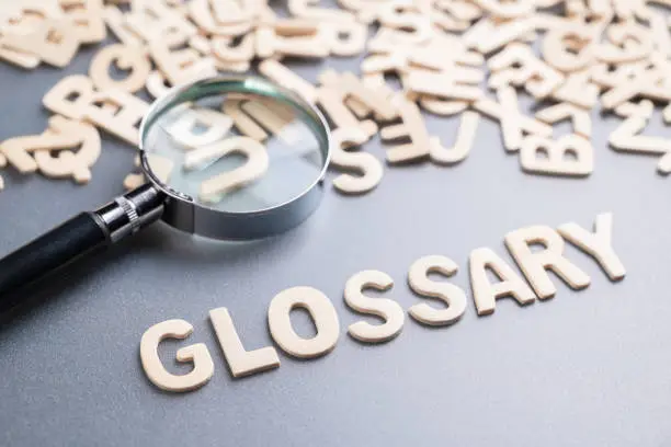 Glossary topic by small wooden alphabets with a magnifying glass