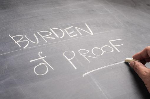 Closeup hand write the text Burden of Proof, on the blackboard, topic of law learning concept