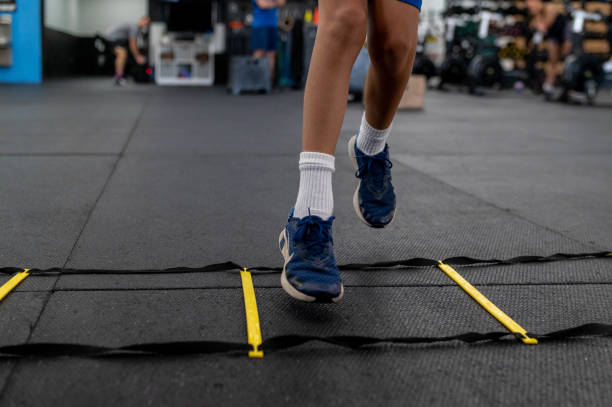 Athlete performing speed drills on agility ladder. stock photo