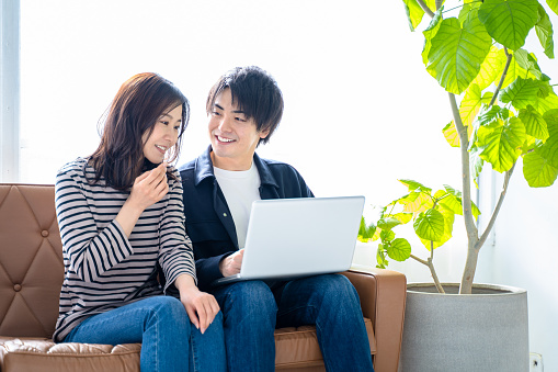 Couple couple-smiling man and woman sitting on the sofa in the living room and searching the net relax