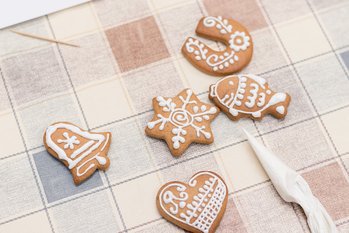glazing traditional gingerbread cookies with Christmas ornaments put on the table