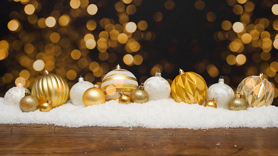 Festive christmas ornaments advent celebration holiday background banner greeting card - Collection of many golden and white modern christmas baubles, christmas balls on snowy wooden table with bokeh lights