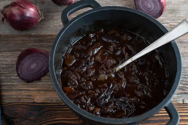 Delicious homemade red onion sauce. Served in a sauce pan isolated on rustic and wooden table background from above with copy space