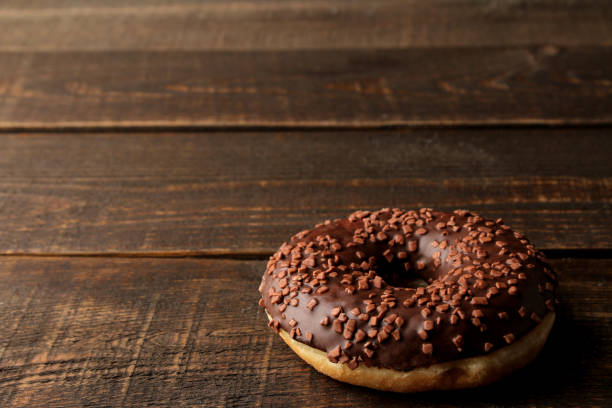 istock Chocolate donut with icing on a brown wooden table with space for an inscription 1440531693