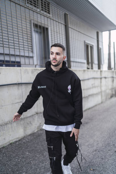 foto vertical de um jovem homem da moda posando em uma roupa de streetwear preta - street style - fotografias e filmes do acervo