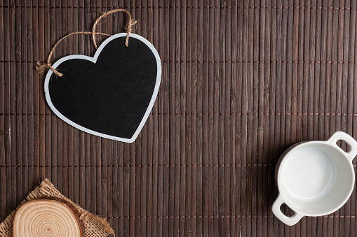 A top view of a wooden surface with a heart decoration and a mug with copy space