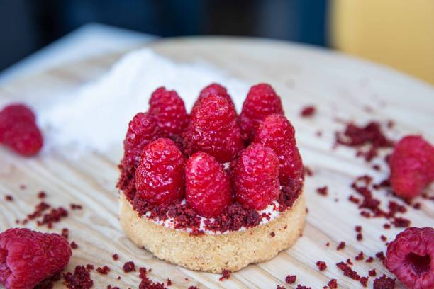 Raspberry Tart on a wooden plate with garnishing.