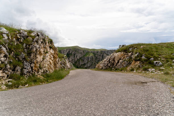 A road through geological formations and rocky mountains under the cloudy sky