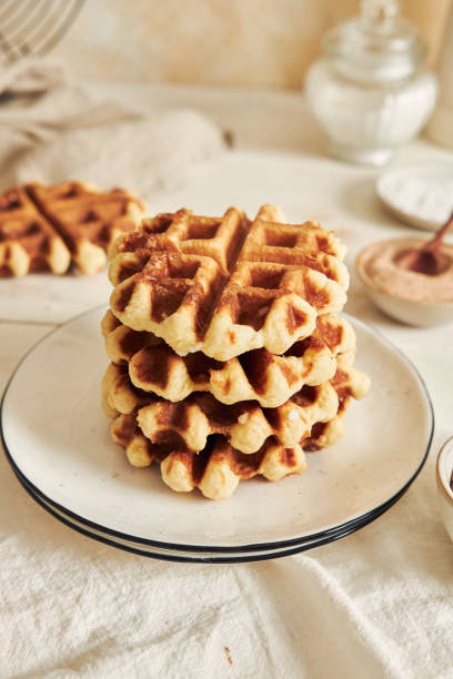 istock Vertical shot of delicious waffles in a pile on a white table 1440535409