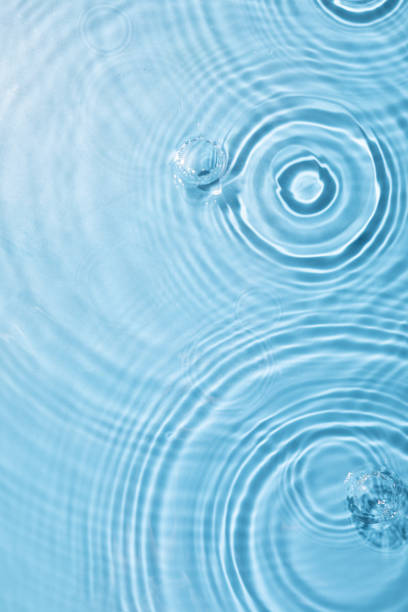 istock Top view closeup of waterdrops falling on the surface and forming a circular shape 1440536421