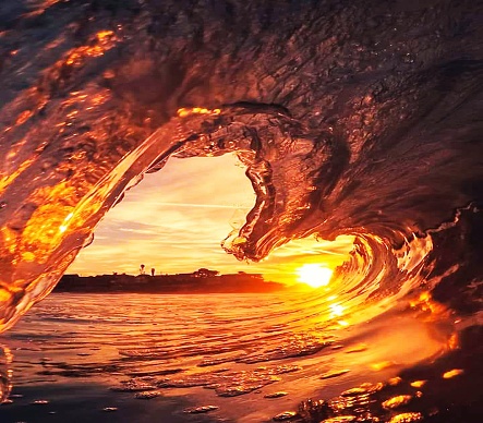 A scenic shot of the sea waves in the shape of a heart at sunset