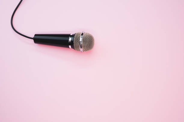 istock Closeup shot of a microphone with a wire isolated on a pink background with a shadow 1440537021