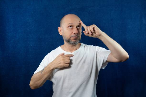 istock Thoughtful bearded bald man posing against blue background 1440538098