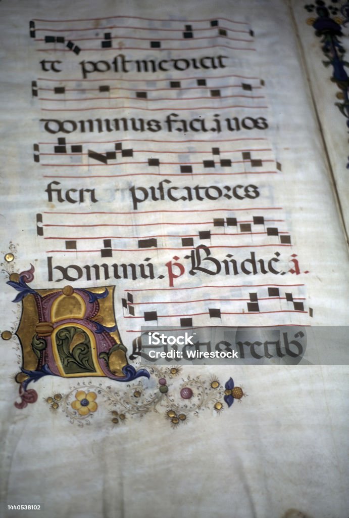 Closeup of an illuminated medieval manuscript on a  parchment with the historical Gregorian chant A closeup of an illuminated medieval manuscript on a  parchment with the historical Gregorian chant Chanting Stock Photo