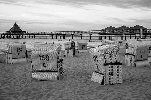 beach chairs against cloudy sky over pier