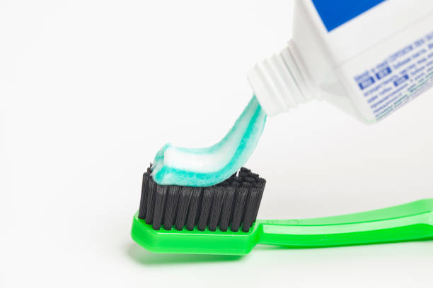 istock Close up of squeezing toothpaste on toothbrush on white background. 1440538741