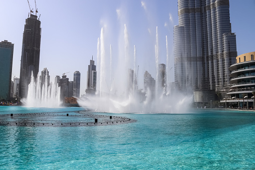 Dubai, United Arab Emirates – August 15, 2020: The Dancing fountains downtown and in a man-made lake in Dubai, UAE in front of the Burj Khalifa on a sunny day with a blue sky.