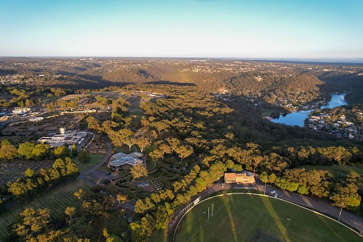 Aerial view of sporting ground, Sutherland Oval, Woronora River and Sutherland suburb surrounded by lush greenery, Sydney, NSW, Australia