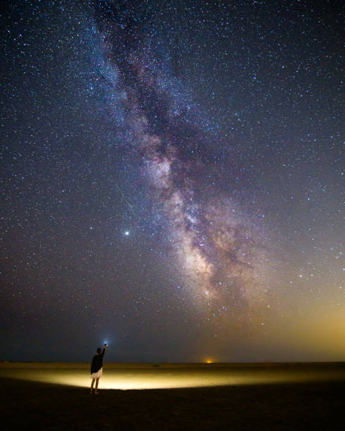 istock Girl pointing the milky way with a flash light 1440540232