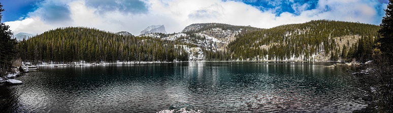 A panoramic view of Bear Lake surrounded by mountains covered with pine forest and snow in winter