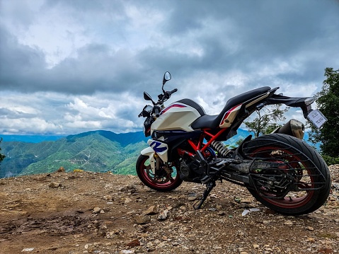 Massoorie, India – July 24, 2022: A BMW G310R motorcycle parked at the edge of the Himalayas under a cloudy sky