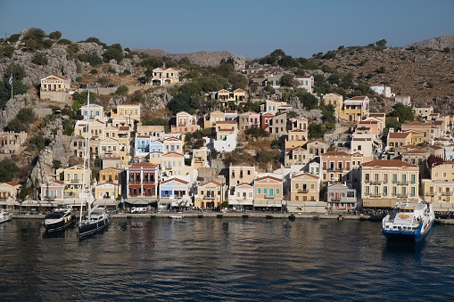 A beautiful view of the Symi Harbor on Symi Island, Greece with boats docked on calm waters at sunset