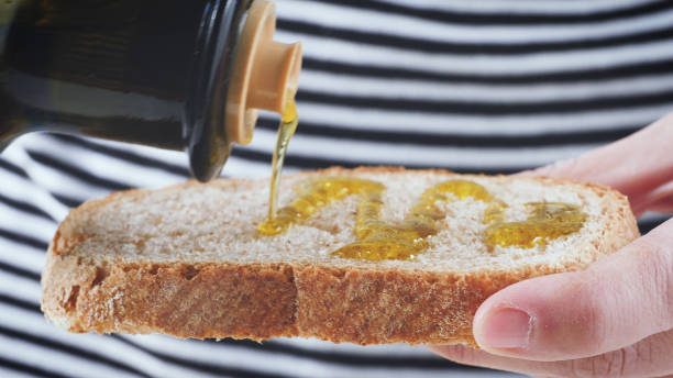 istock Selective focus shot of a male adding extra virgin oil on a bread 1440543039