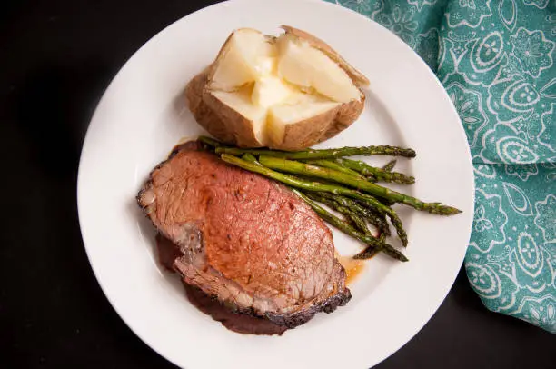 organic prime rib roast dinner with baked potato and asparagus