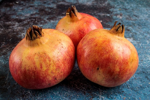 A closeup shot of three appetizing pomegranates on a rustic background