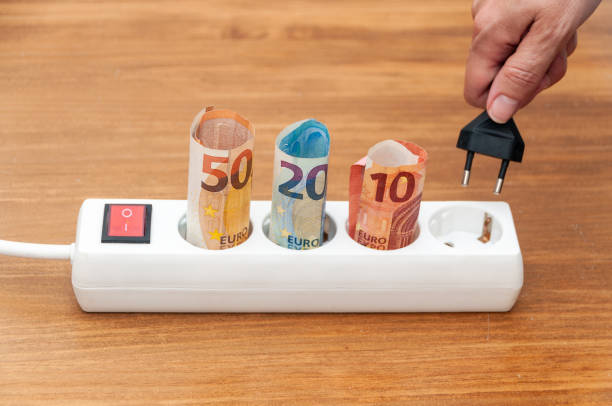 istock White power strip with rolled euro banknotes and a hand holding a plug 1440544619