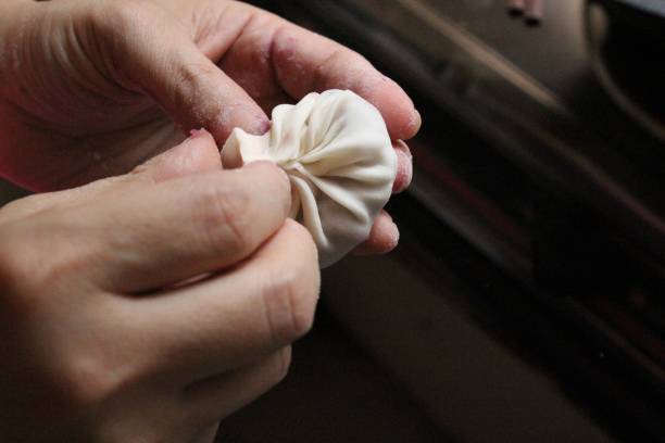Closeup shot of a hand folding dough to make a dumpling