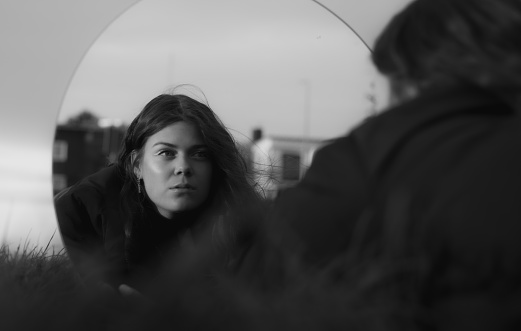 Young woman looking in the mirror self reflecting