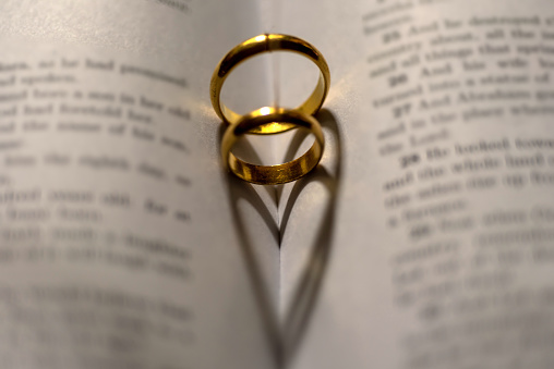 A closeup of wedding rings forming heart shapes on the bible - concept of love and marriage