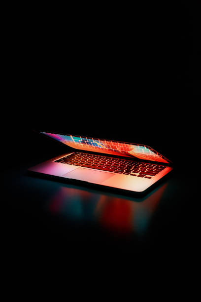 istock Vertical shot of a half-open laptop isolated on dark background 1440548550