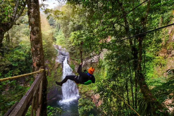 A young man riding on a zip line rope in an extreme adventure jungle in XicVeracruz, Mexico