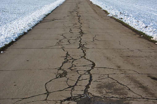 A closeup of a cracked asphalt road in winter