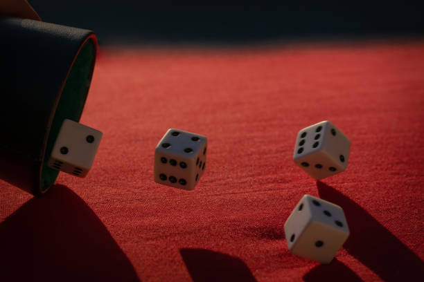 istock Selective focus shot of dices falling out of the dice shaker on a red surface 1440553209