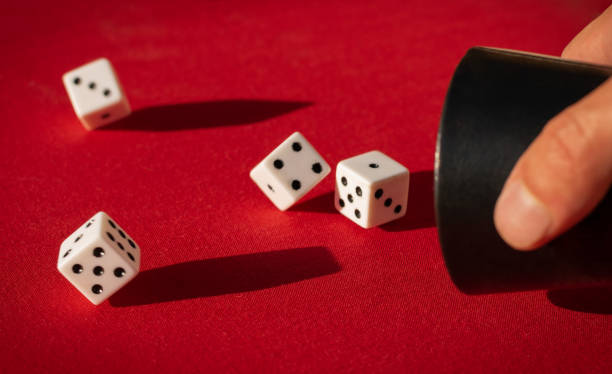 istock Selective focus shot of dices falling out of the dice shaker on a red surface 1440553214